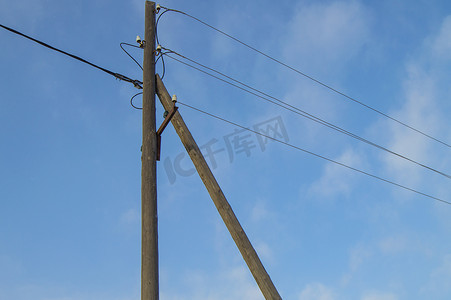 绝缘体摄影照片_蓝天背景上带电线和绝缘体的木制旧 0.4 kV 电源线支架