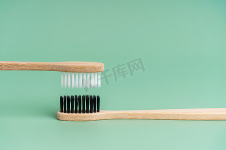 浅绿色背景上有白色和黑色刷毛的两把环保抗菌竹木牙刷。