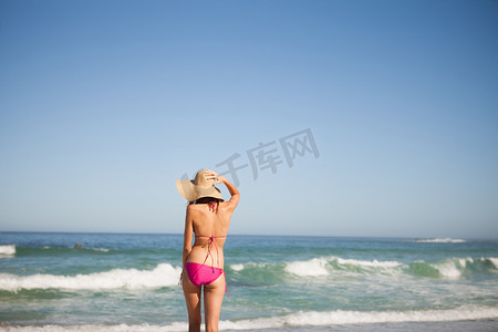 海滩2024摄影照片_一位身穿沙滩装的年轻女子站在前面的背影
