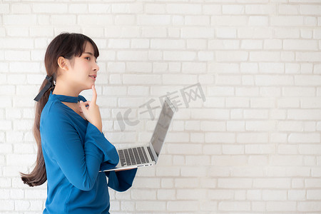 美丽的亚洲年轻女性嬉皮士在水泥混凝土背景下使用工作笔记本电脑思维理念，女孩怀疑和问题与计算机互联网在线，自由职业者和商业概念。