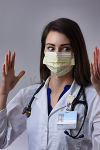 黑衣蒙面人摄影照片_洗手后高举双手的蒙面医疗专业人员。