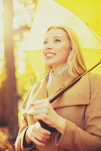 大雨伞摄影照片_秋天公园里带黄色雨伞的女人