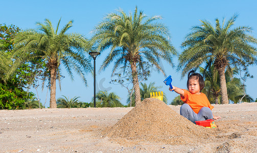 开朗的女儿女孩有趣地挖沙子玩玩具