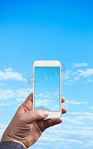 广告蓝天白云摄影照片_男子手持手机拍摄蓝天白云