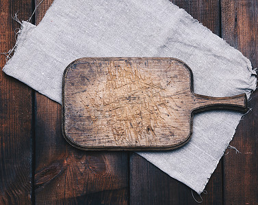 旧棕色矩形木制厨房切板和桌上的灰色亚麻餐巾