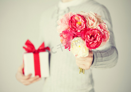 红色花束包装摄影照片_拿着一束鲜花和礼品盒的男人