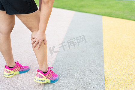 腿部受伤摄影照片_女胖赛跑运动员腿部受伤和疼痛。
