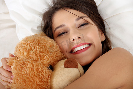 抱着泰迪熊躺在床上的女孩