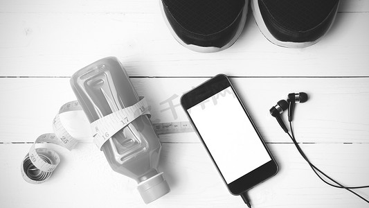 苹果手机黑色手机摄影照片_跑鞋、橙汁、卷尺和手机黑色和白色