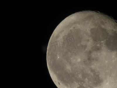 通过长焦相机拍摄的黑色夜空中的月亮特写。