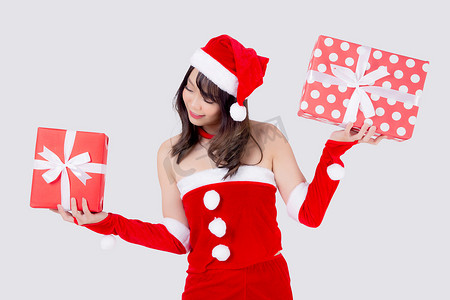 美丽的肖像年轻亚洲女人快乐地拿着红色礼品盒，在圣诞节假期中兴奋地与白色背景隔离，亚洲女孩惊喜并在节日的圣诞节和新年庆祝。