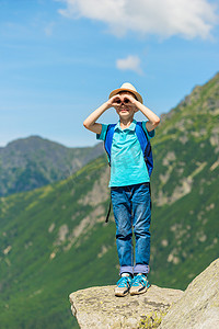 旅行男孩看着美丽的山脉，站在石头上
