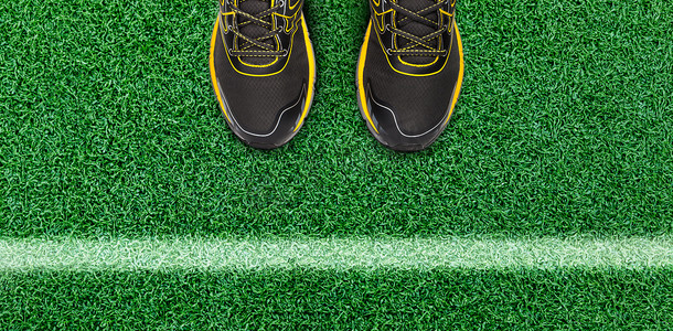男运动鞋子摄影照片_草地上的白色条纹和男鞋