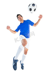 蓝色运动服摄影照片_蓝色的足球运动员跳向球