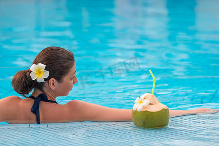 泳池里穿着比基尼的放松女人，还有多汁的椰子