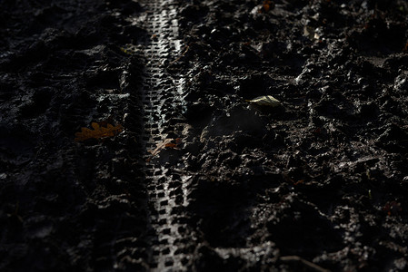 阳光照射阴影摄影照片_3 - 深冬泥浆中被阳光照射的自行车轮胎痕迹的深色特写