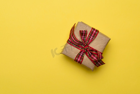方形盒子，里面有用牛皮纸包裹的礼物，并用红色丝带系着