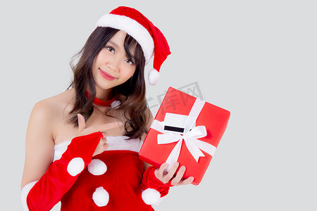 美丽的肖像年轻亚洲女人兴奋地拿着红色礼盒，在圣诞节假期里有卡片或标签，与白色背景隔离，亚洲女孩惊喜，并在节日的圣诞节和新年庆祝。