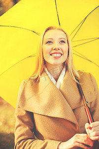 秋天公园里带黄色雨伞的女人