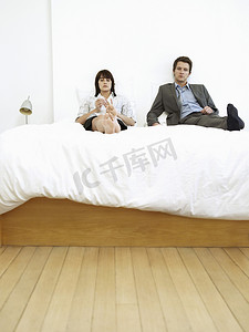 年代感卧室摄影照片_坐在床上的年轻商业夫妇，忽略