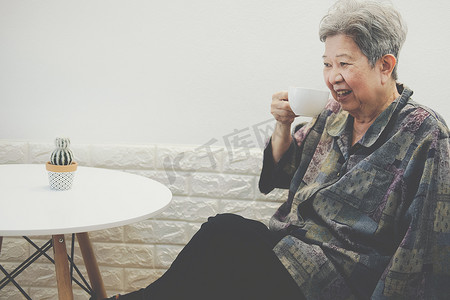年长的老年妇女在家喝热摩卡咖啡茶。