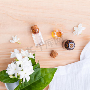 香薰瓶摄影照片_香薰油瓶排列在木制背景板上的茉莉花