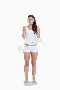 微笑的女人站在称重 s 上竖起大拇指