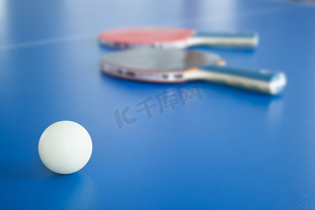 乒乓球运动摄影照片_背景有球拍的白色乒乓球