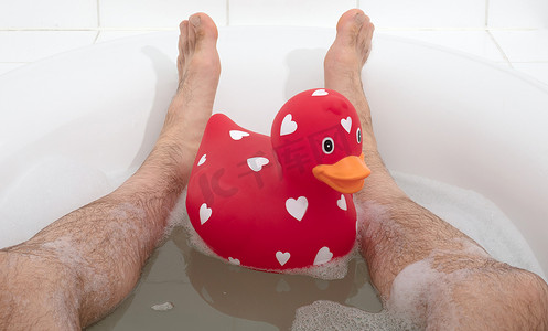 大鸭鸭摄影照片_男人的脚在浴缸里，有大橡皮鸭