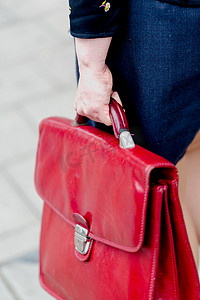 红色公文包摄影照片_年轻成人女商人拿着红色皮革公文包