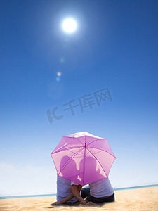 在海滩上的伞下接吻的情侣