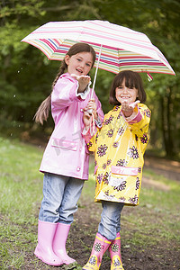 雨中户外的两姐妹撑着伞微笑