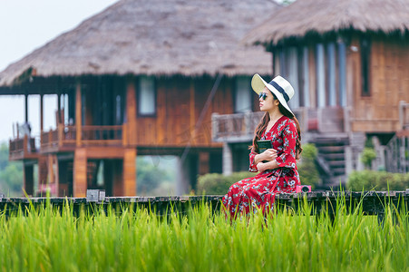 年轻女子坐在老挝万荣的绿色稻田木路上。