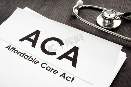 负担得起的医疗法案 ACA 和听诊器在一张木桌上。
