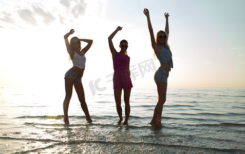 快乐的女性朋友在沙滩上跳舞