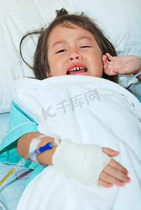 小女孩的哭泣摄影照片_在病床上哭泣的生病的小女孩