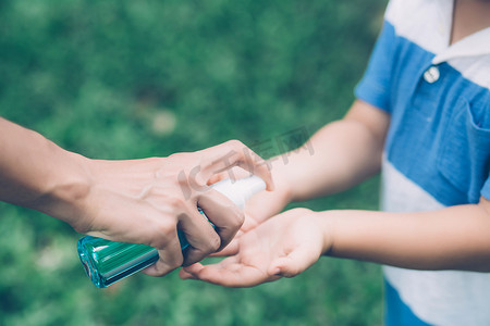 母亲用消毒剂照顾儿子以保护流感病毒或 covid-19 在户外清洁手，儿童洗手以确保公共、卫生和生活方式概念中流行病爆发的安全。