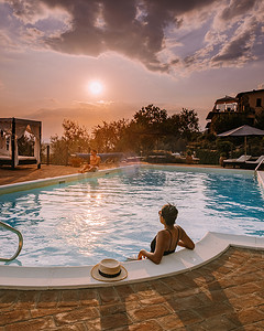 日落真实摄影照片_意大利带游泳池的豪华乡间别墅，意大利豪华别墅度假的情侣，男人和女人看日落