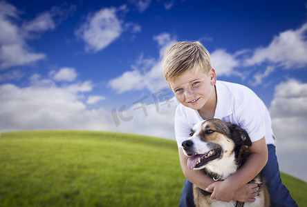 英俊的小男孩在草地上和他的狗玩耍