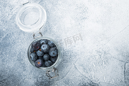 蓝色文字纹理摄影照片_玻璃瓶中的蓝莓，平躺着，有文字空间，有纹理的背景