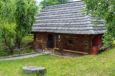 一栋茅草屋顶的乡村老房子位于绿色草坪上，一块铺好的石头通向它。
