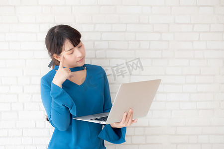 美丽的亚洲年轻女性嬉皮士在水泥混凝土背景下使用工作笔记本电脑思维理念，女孩怀疑和问题与计算机互联网在线，自由职业者和商业概念。
