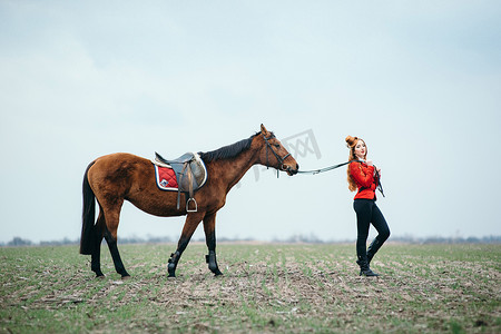 红色羊毛衫和黑色高筒靴的红发骑师女孩