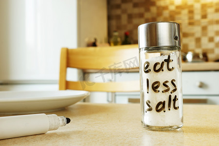 咸摄影照片_少吃在玻璃容器上手写的盐。