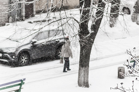 一个路人在大雪中穿过白雪皑皑的城市院子