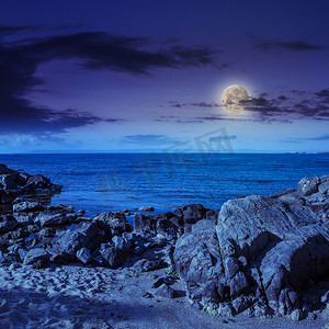破碎月亮摄影照片_海浪在夜晚的沙滩上破碎