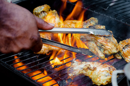 厨师在烤架上用手转动食物做混蛋烧烤 BBQ 鸡