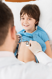 医生用听诊器检查微笑的小男孩的背影