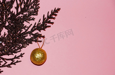 粉红色雪花摄影照片_粉红色背景中棕色镀金树枝上的金球，圣诞空白