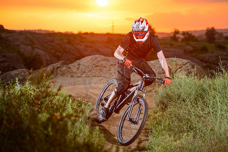 专业骑自行车的人在日落时分在山上的岩石小径上骑自行车。